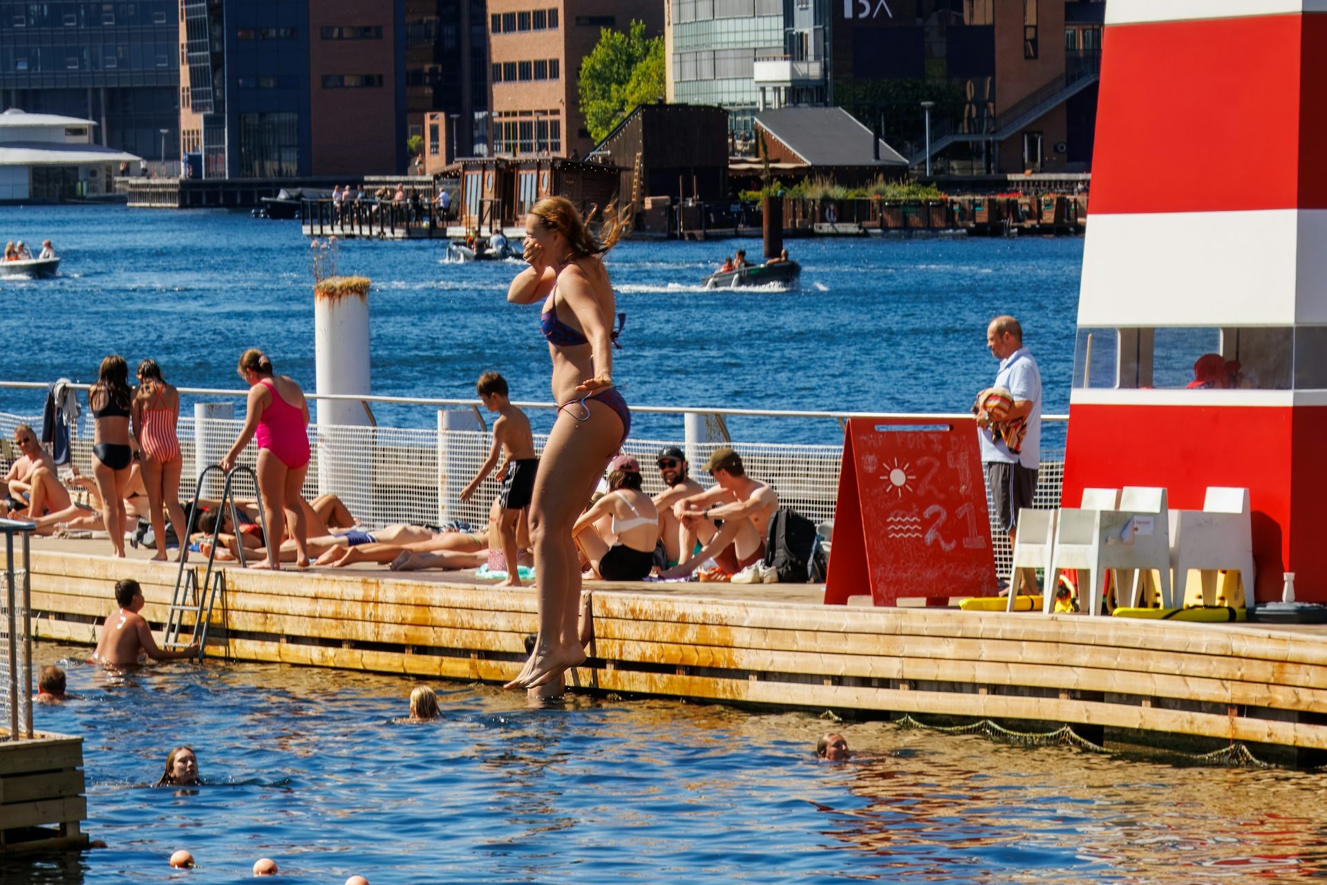 Woman jumping into the water from a wooden platform in the canals of Copenhagen, Denmark, during summer, August 16, 2025.