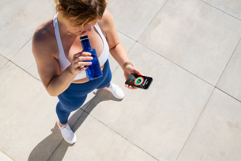 Une femme fait une pause pendant son sport et regarde son compteur de marche sur son smartphone.