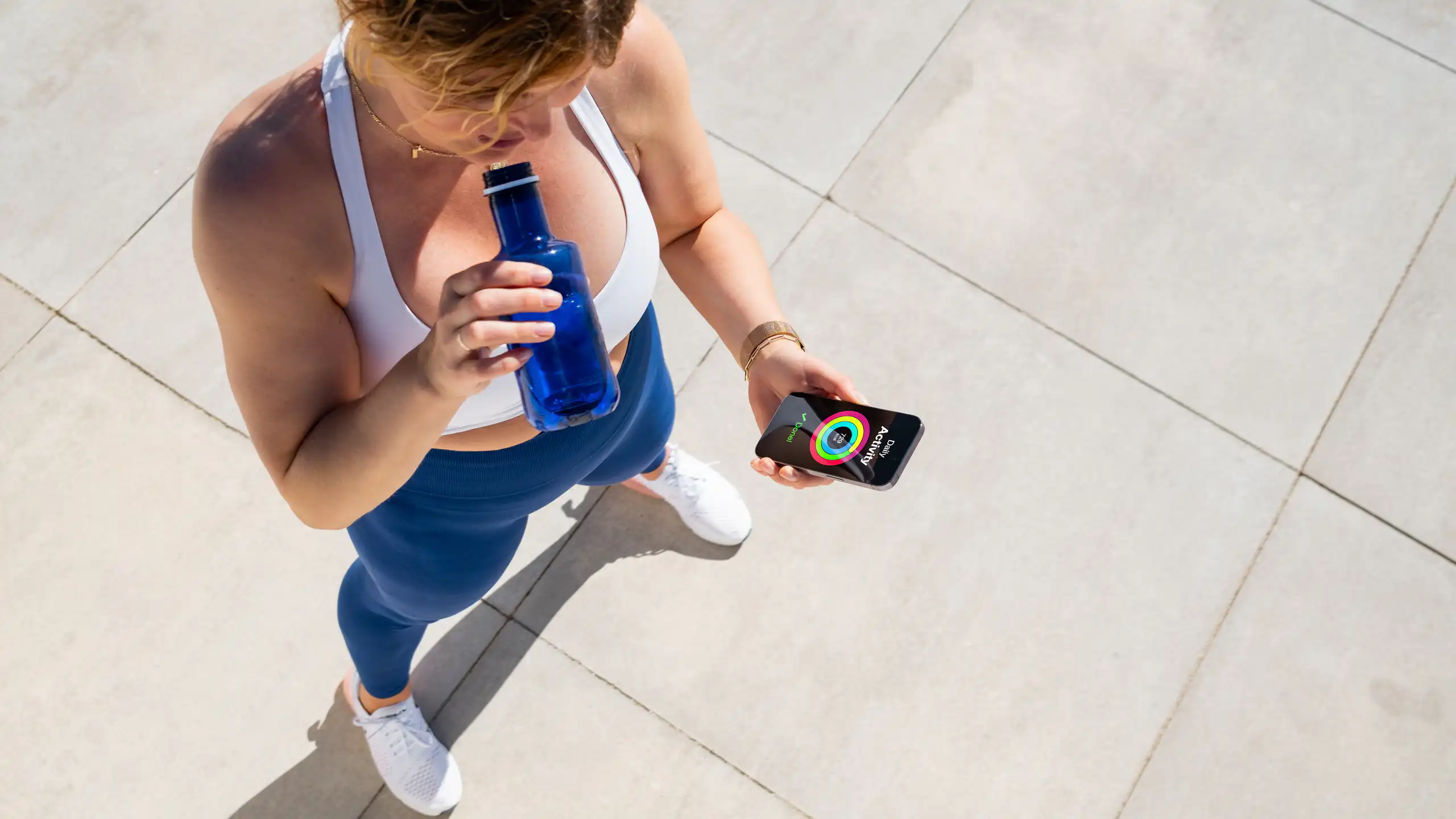Une femme fait une pause pendant son sport et regarde son compteur de marche sur son smartphone.