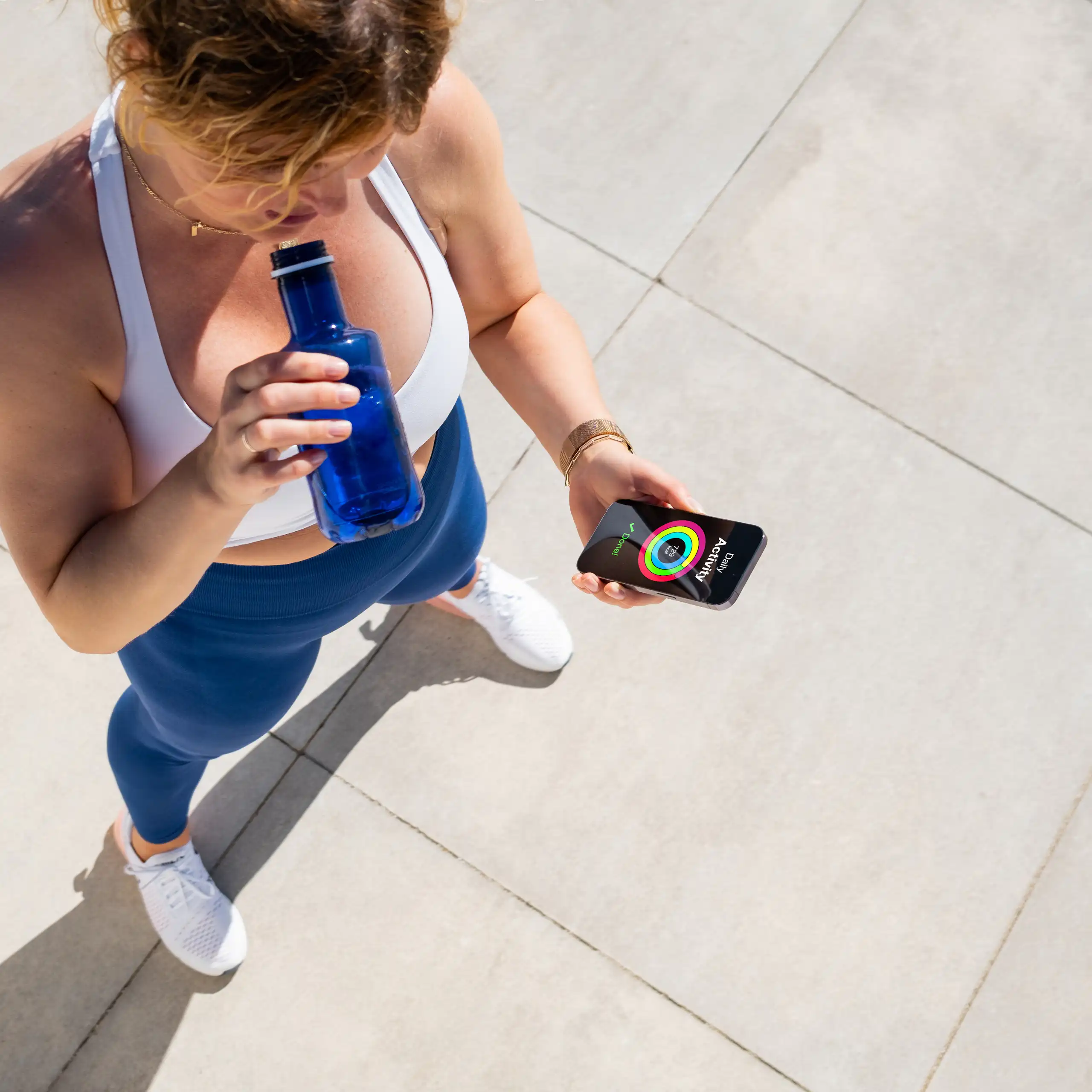 Une femme fait une pause pendant son sport et regarde son compteur de marche sur son smartphone.