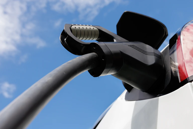 a charger plugged into an electric vehicle against blue sky.