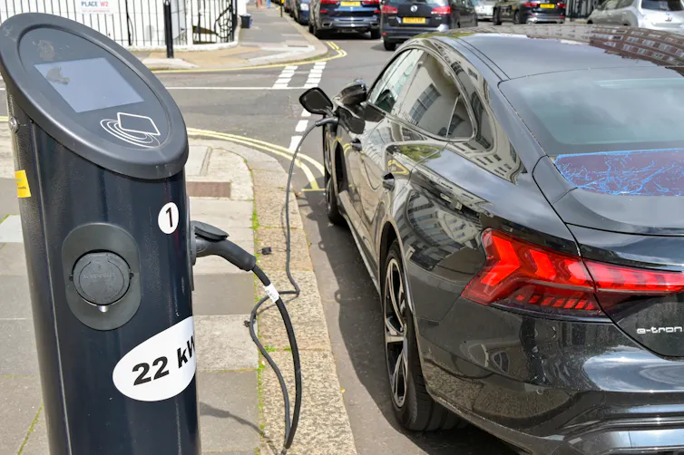 an electric vehicle plugged into a kerbside charger on suburban street.