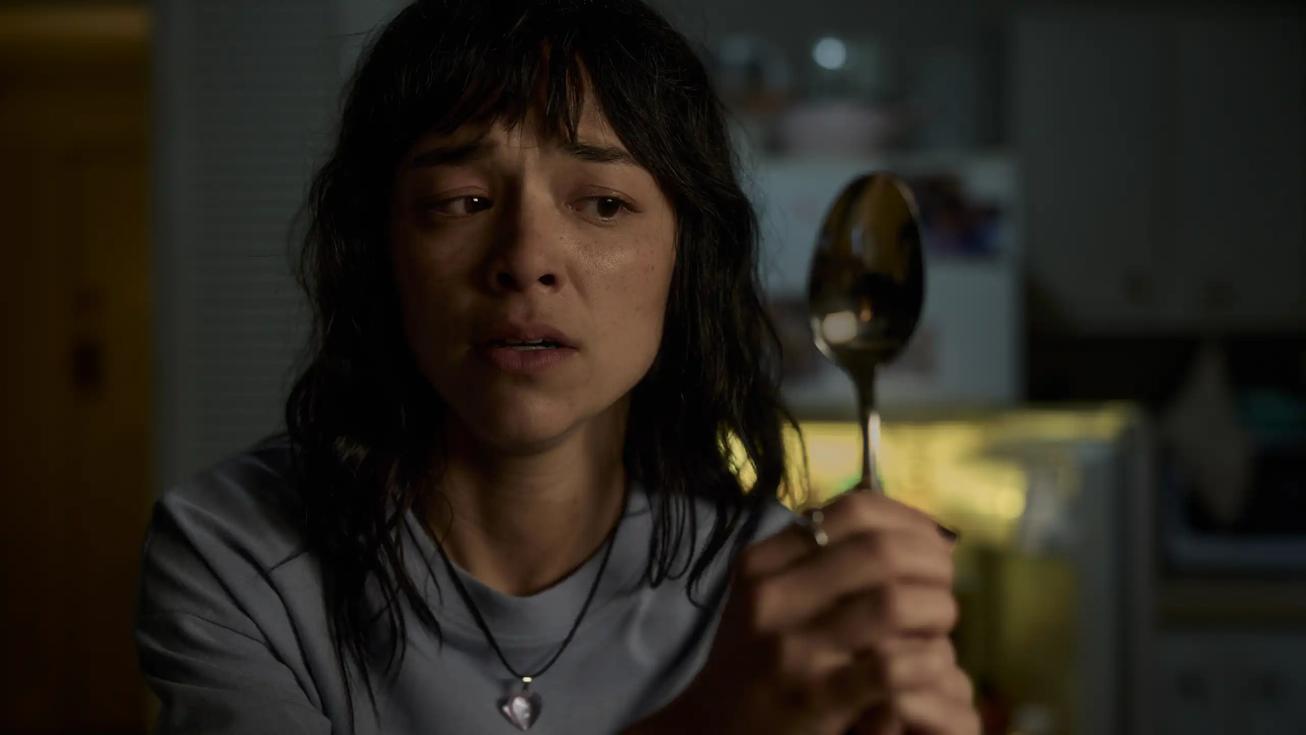 Production image: Hana looks at her reflection in a spoon.