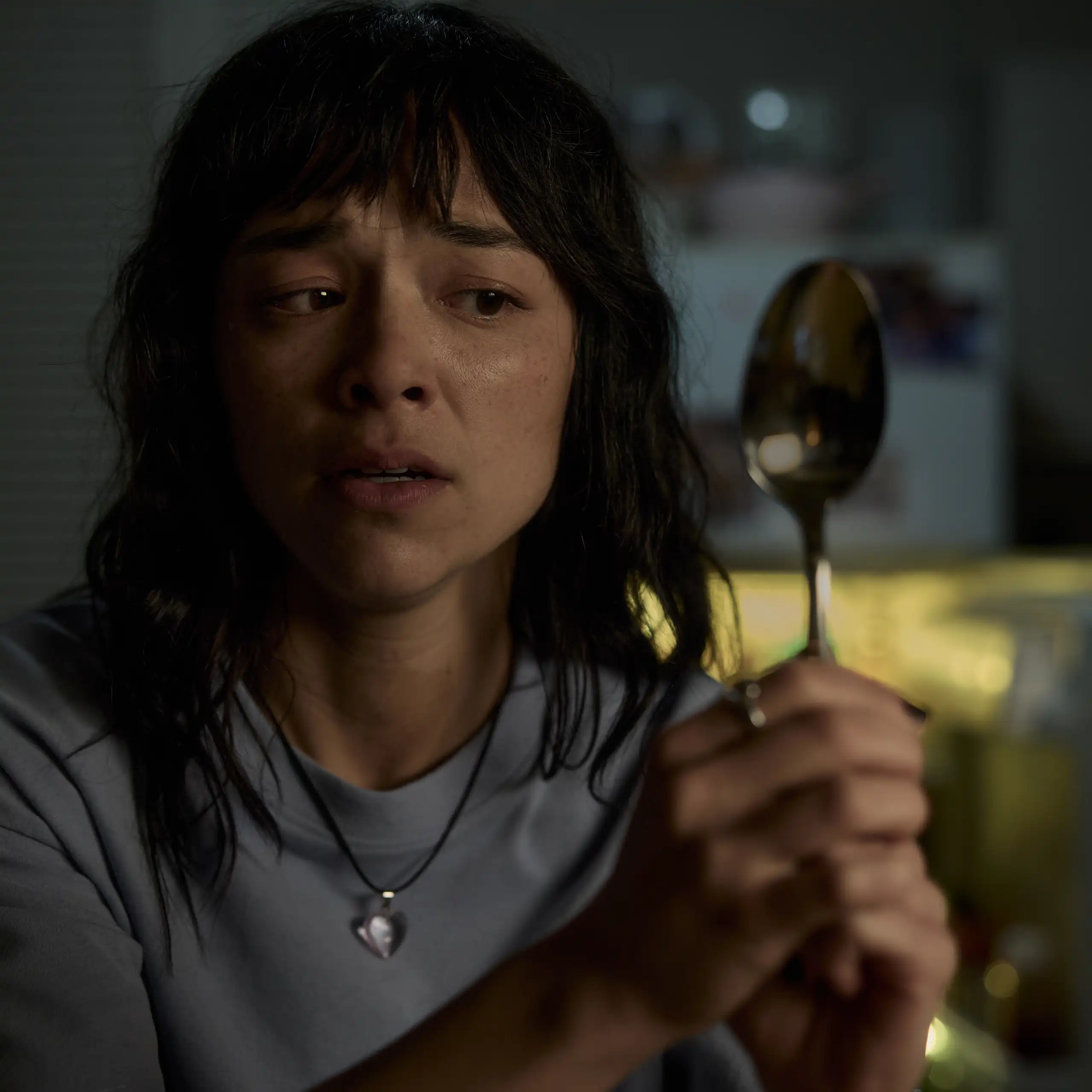 Production image: Hana looks at her reflection in a spoon.