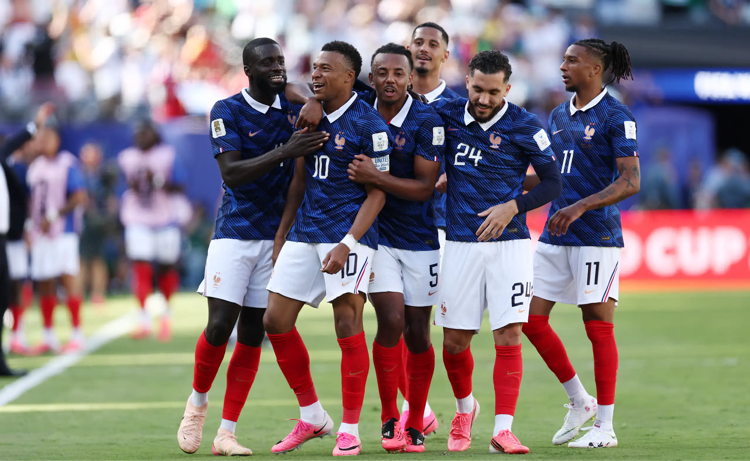 France striker Kylian Mbappé is congratulated by his teammates on the football field.
