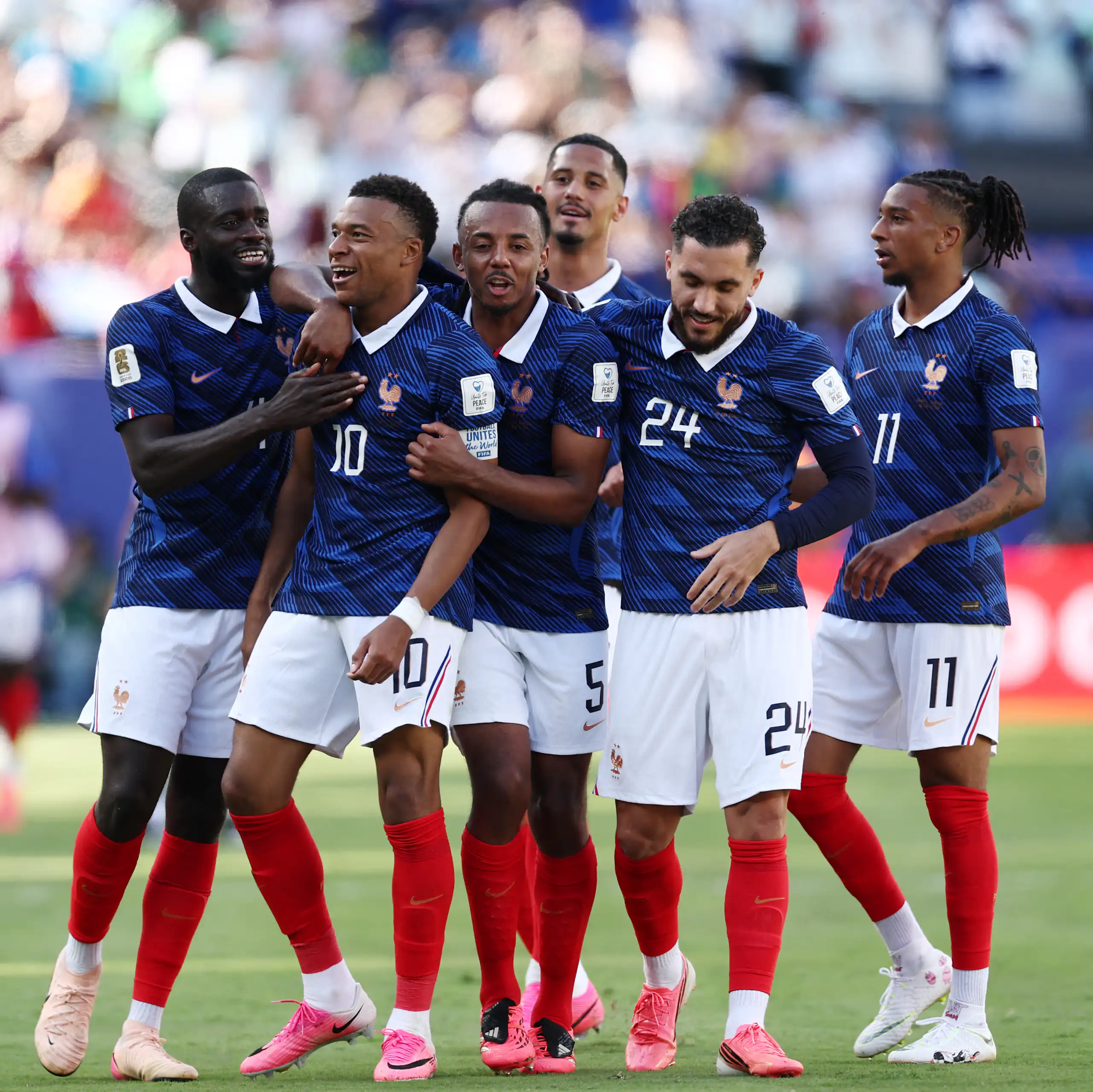 France striker Kylian Mbappé is congratulated by his teammates on the football field.