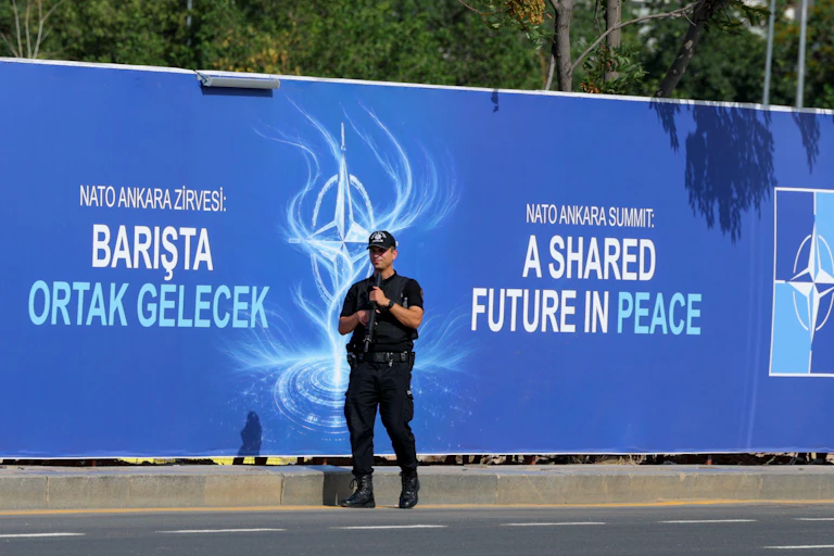 A Turkish police guard stands with his gun raised in front of a billboard advertising the 2026 Nato summit in Ankara, Turkey.
