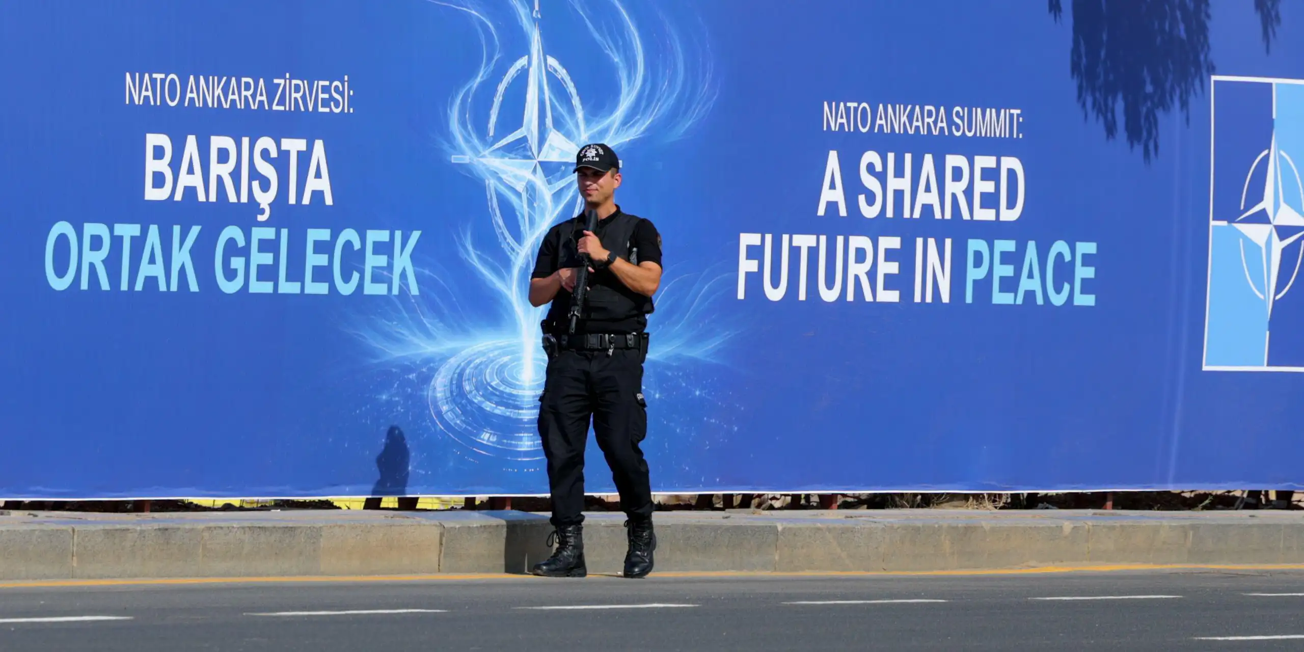 A Turkish police guard stands with his gun raised in front of a billboard advertising the 2026 Nato summit in Ankara, Turkey.