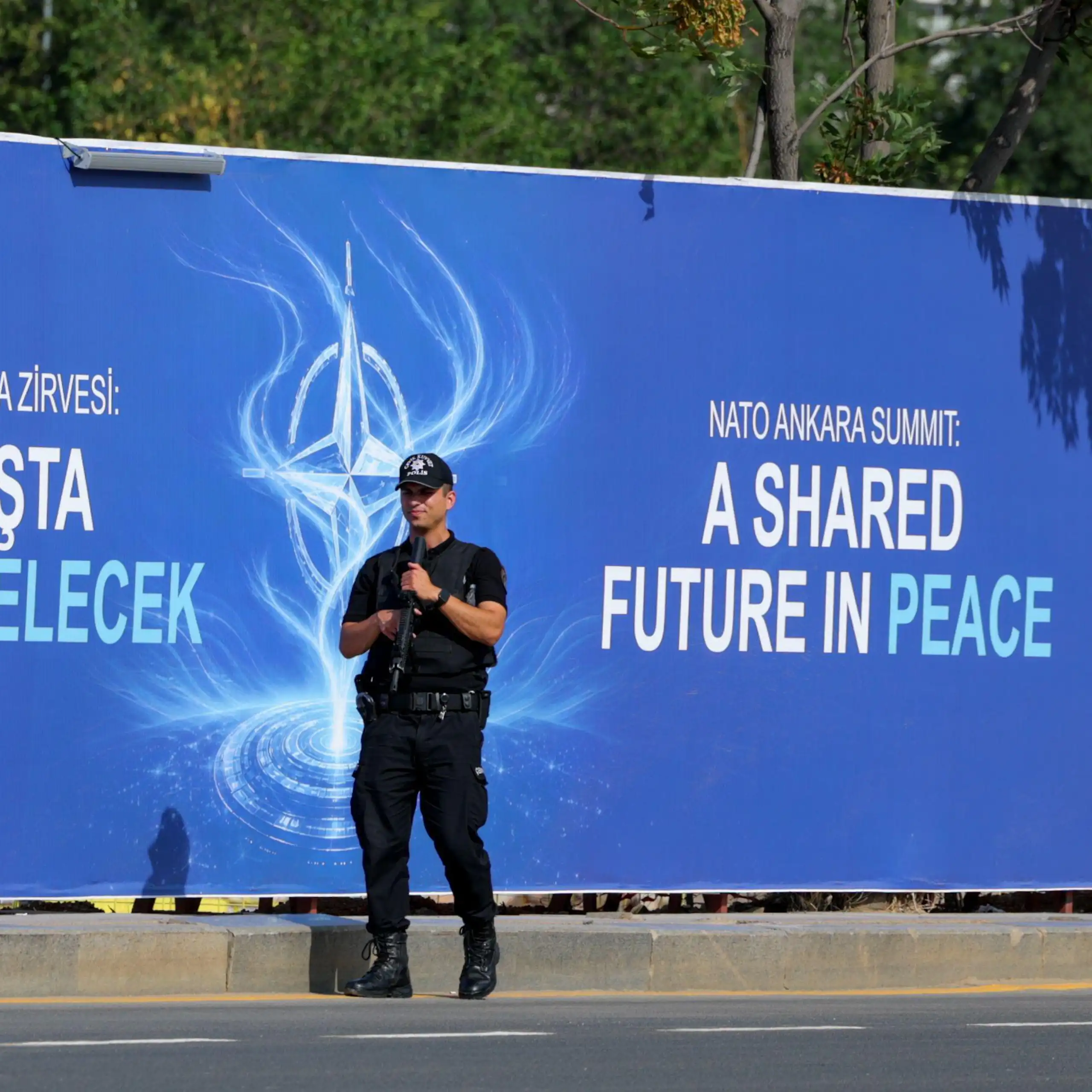 A Turkish police guard stands with his gun raised in front of a billboard advertising the 2026 Nato summit in Ankara, Turkey.