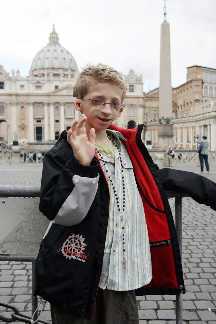 A boy poses for the camera and waves his hand.