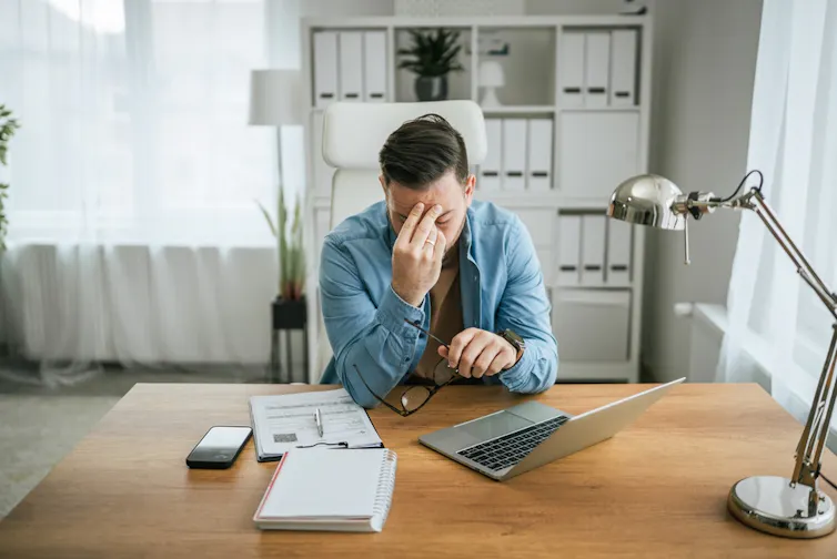 A man sitting at his desk, looking stressed.