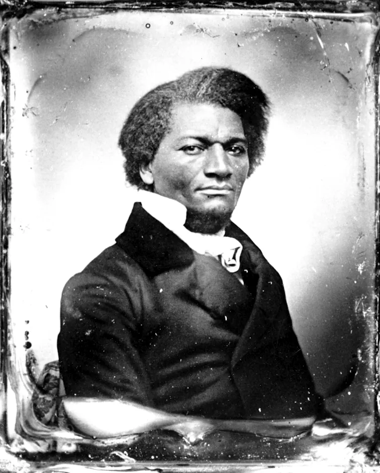 A man with thick, dark hair, wearing a black coat over a white shirt, looking steadily at the camera in an antique photo.