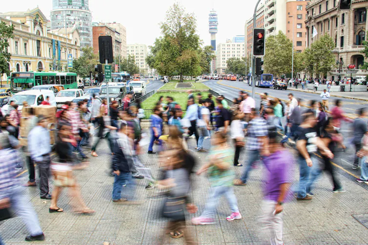 Cómo la inteligencia artificial y los datos digitales están dando forma a nuestra comprensión de la migración 2 Imagen borrosa de gente caminando con ropa colorida en un moderno centro de la ciudad.
