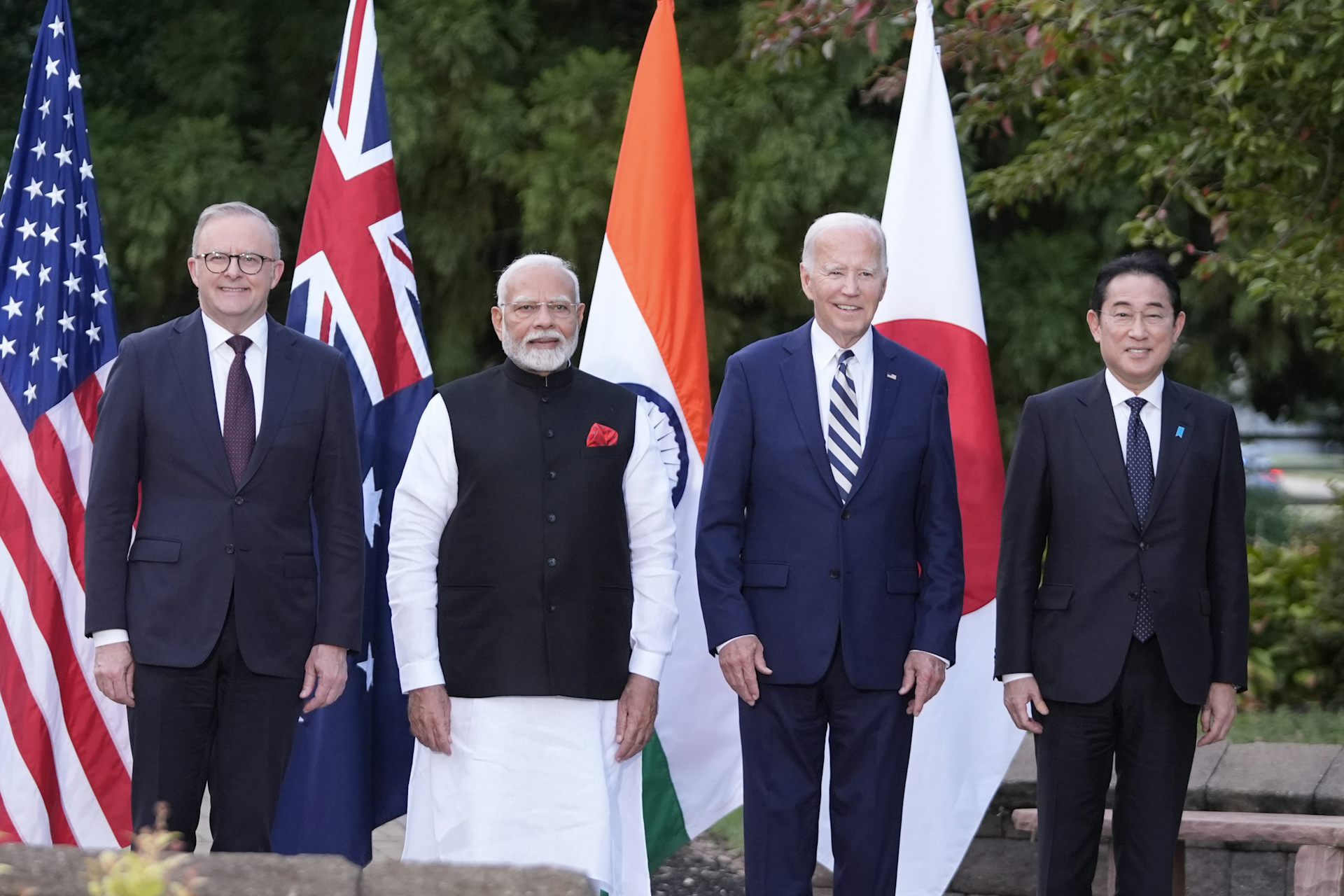 Four men lined up in front of four flags