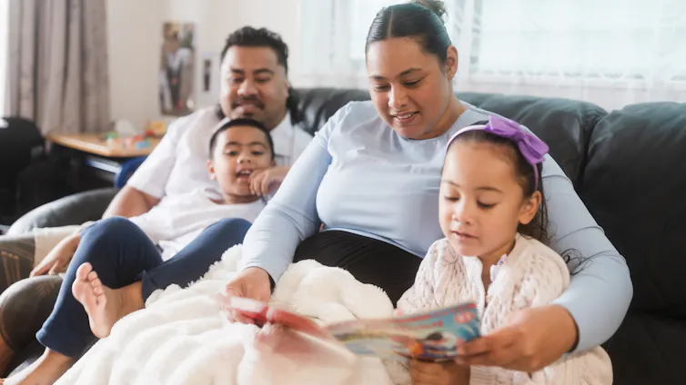 A family relaxing with their children, reading on the sofa