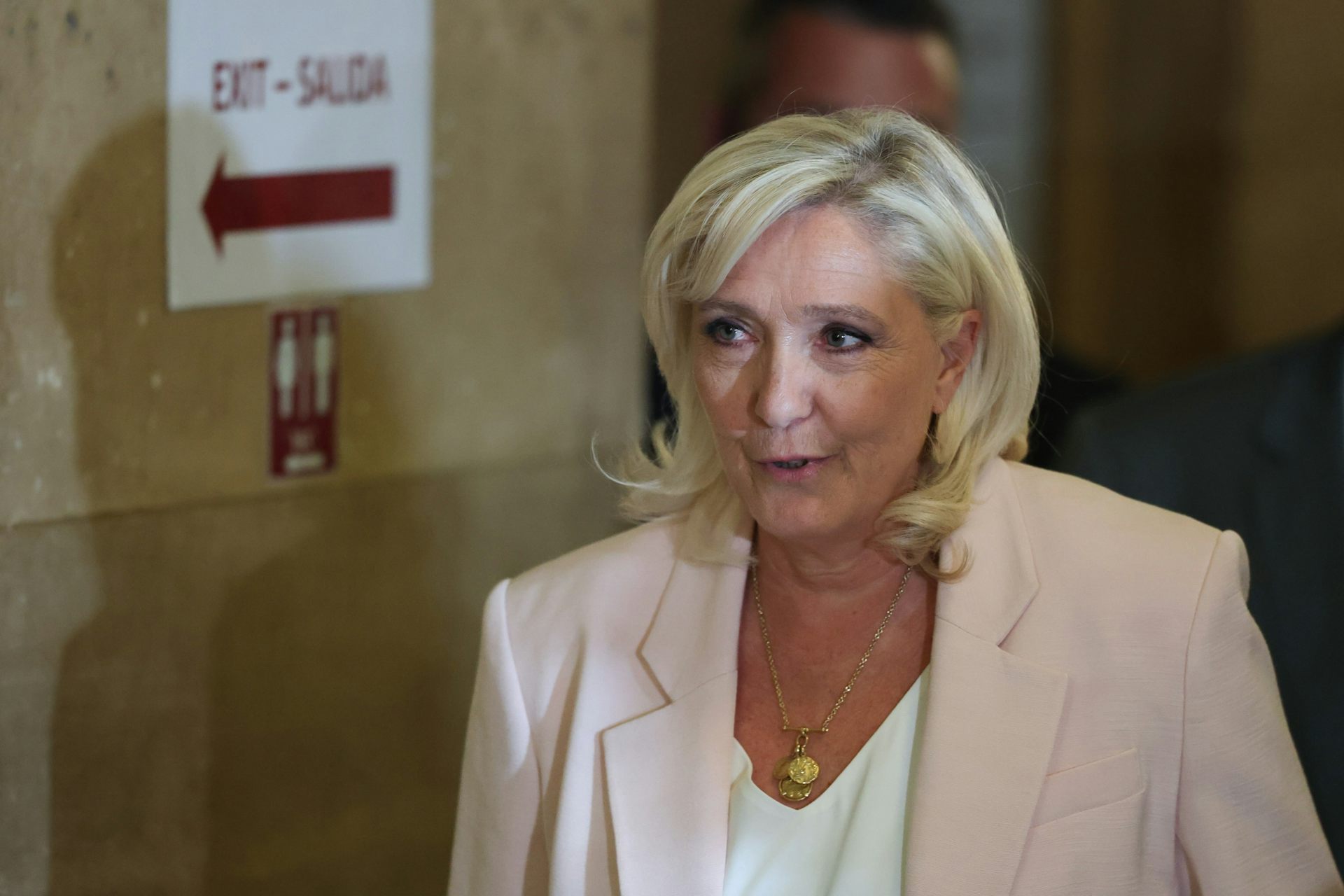 Marine Le Pen dressed in white arrives at a courtroom.