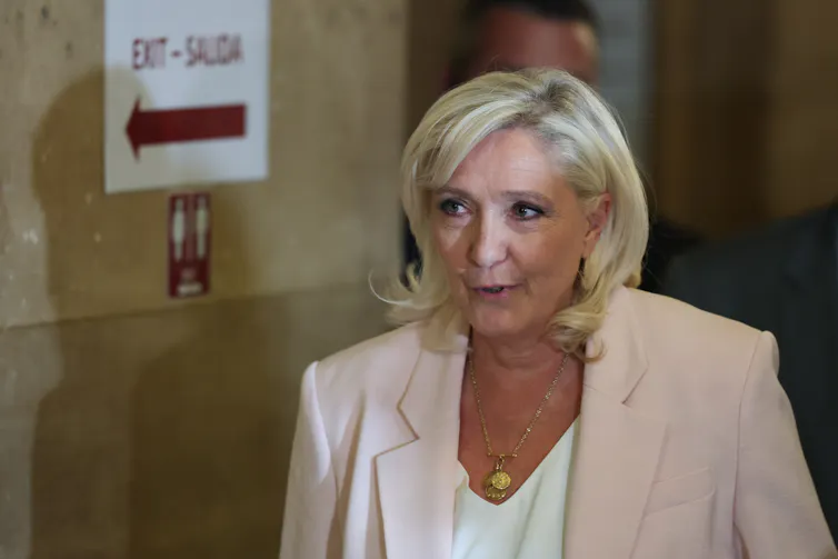 Marine Le Pen dressed in white arrives at a courtroom.