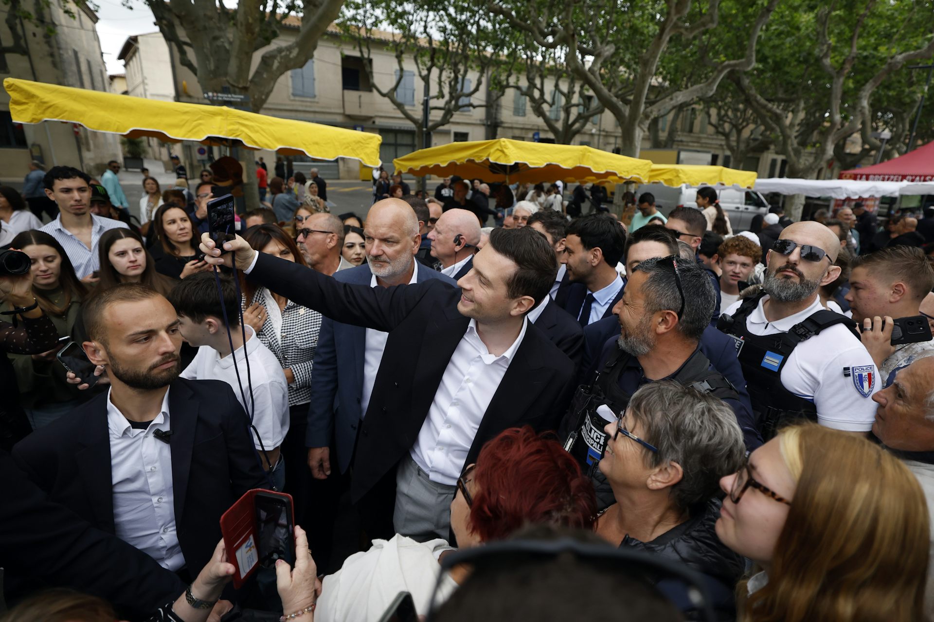 French politician Jordan Bardella, surrounded by a large crowd of people.
