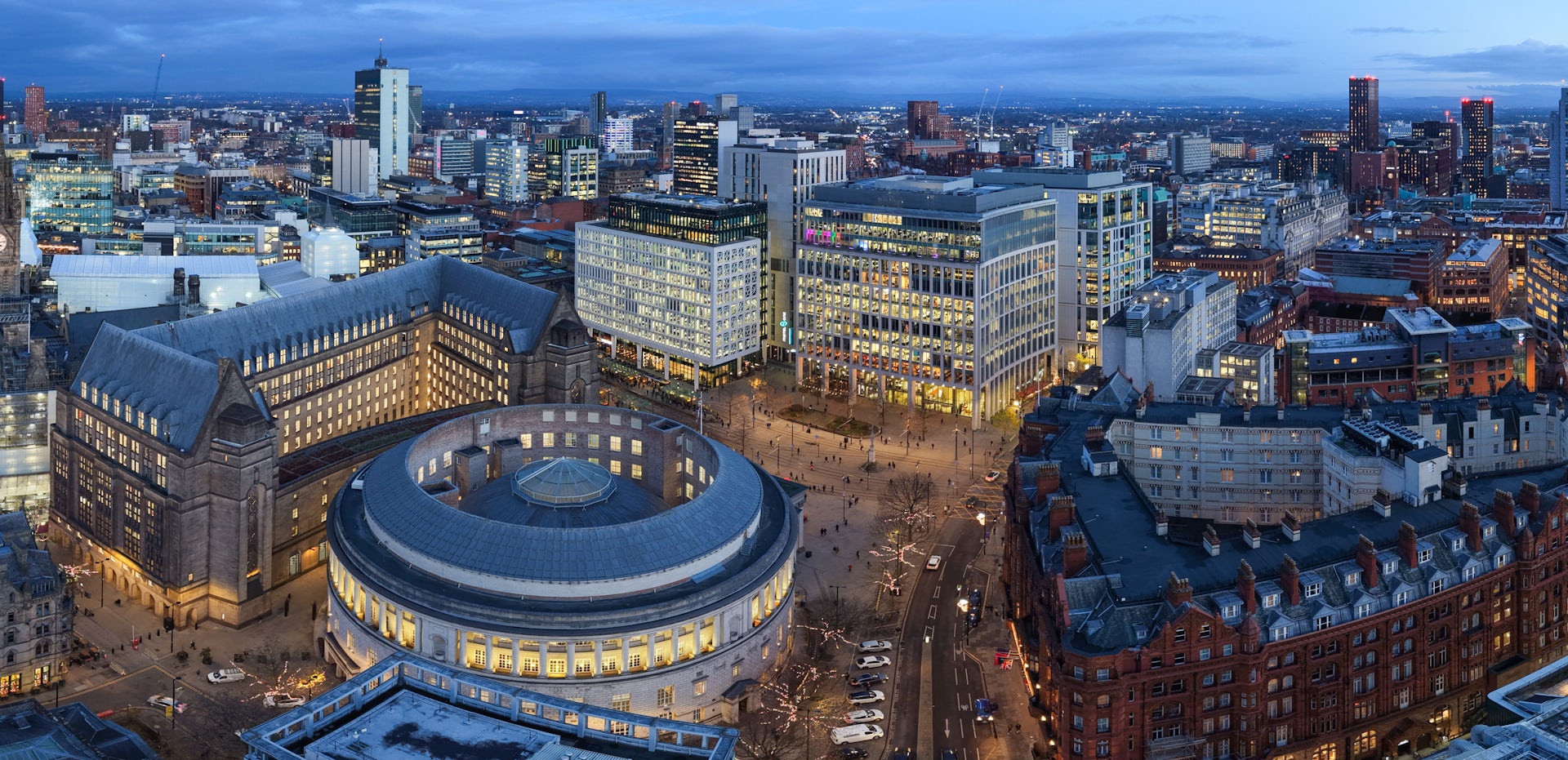 Aerial image of Manchester at dusk, showing glowing winter lights, festive streets and a vibrant seasonal city atmosphere.