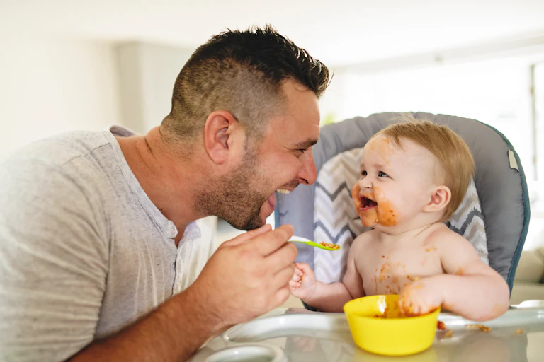 Father feeds happy baby
