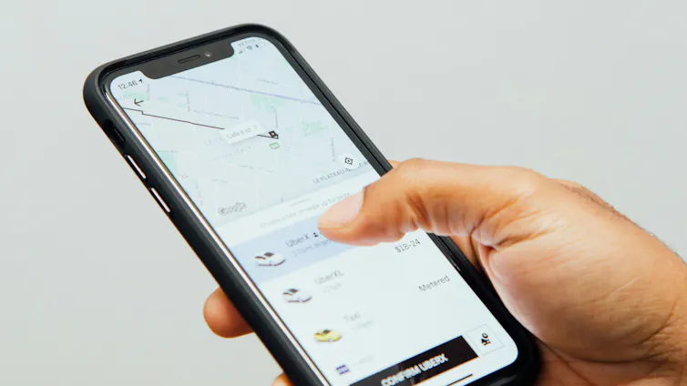 A person holds a smartphone while ordering a ride on a ride-share app.