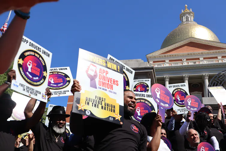 Rideshare drivers hold signs at a rally outside the Massachusetts State House in Boston to celebrate the establishment of their first-ever union in the U.S.
