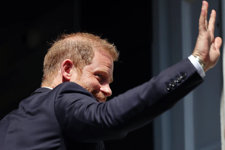 Photo of Prince Harry from behind, waving as he enters an event