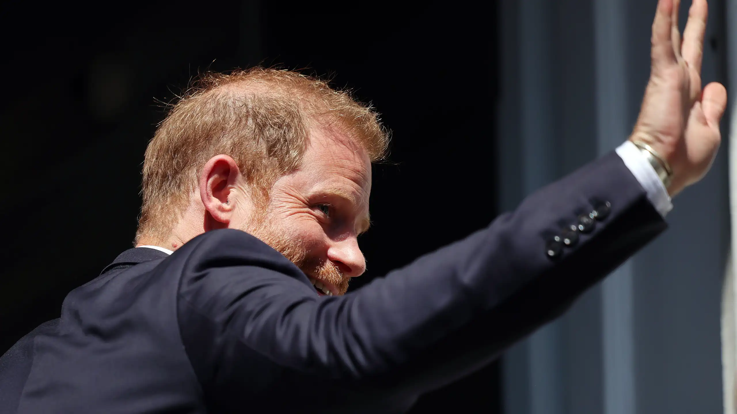 Photo of Prince Harry from behind, waving as he enters an event