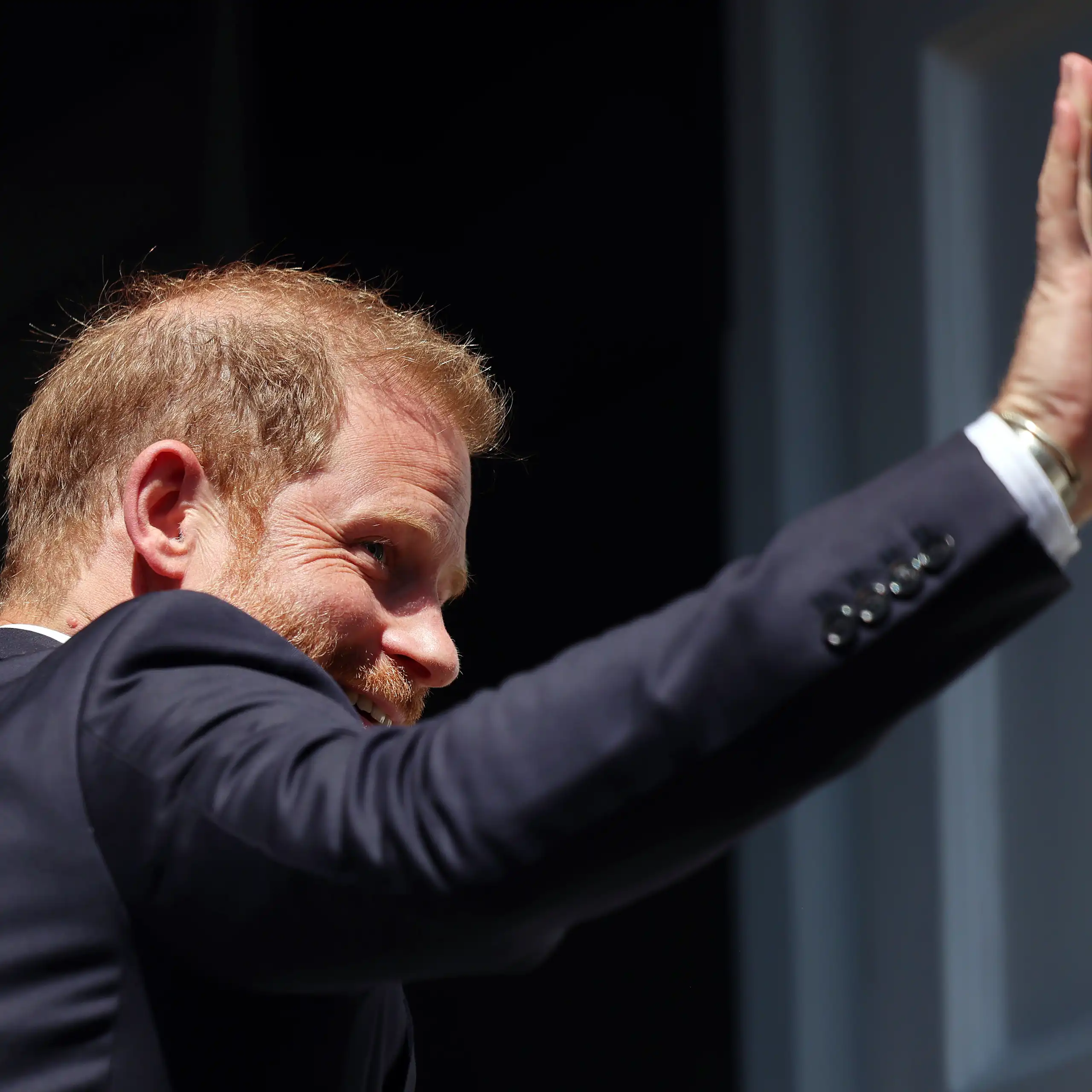 Photo of Prince Harry from behind, waving as he enters an event
