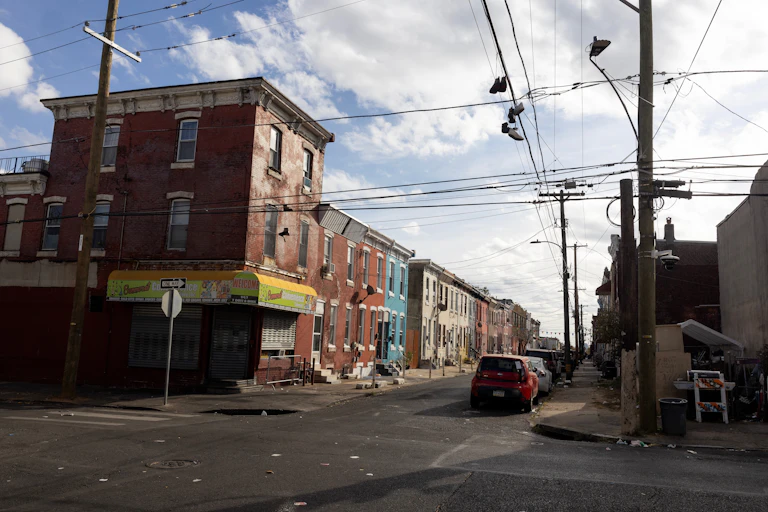 A blighted urban block with colorful rowhomes on a sunny day