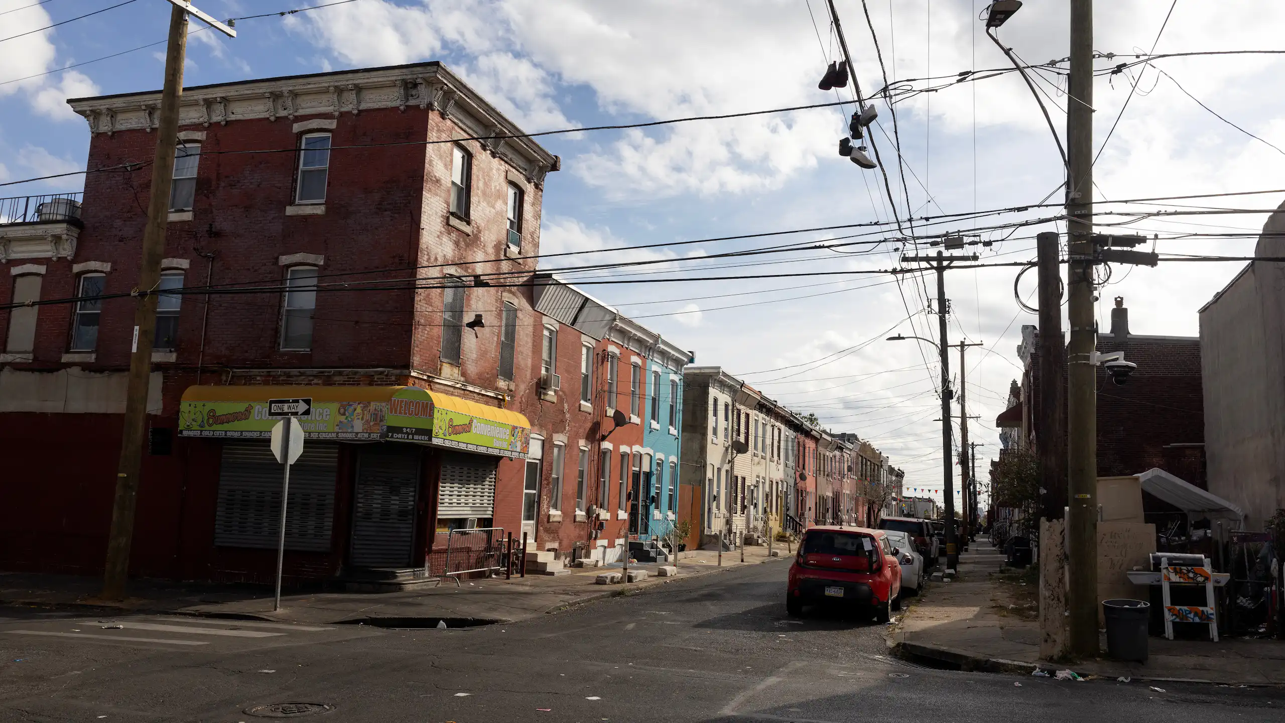 A blighted urban block with colorful rowhomes on a sunny day