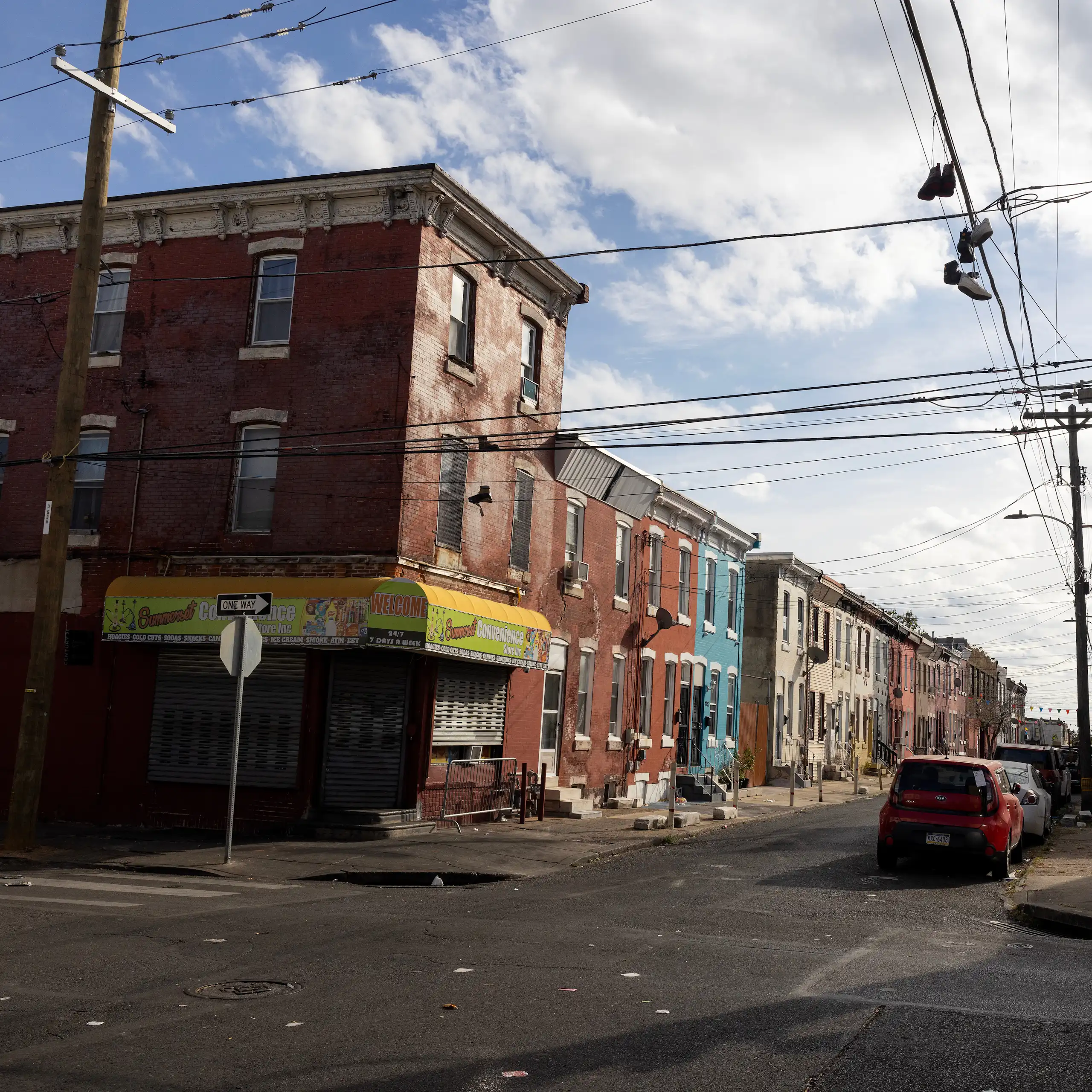 A blighted urban block with colorful rowhomes on a sunny day