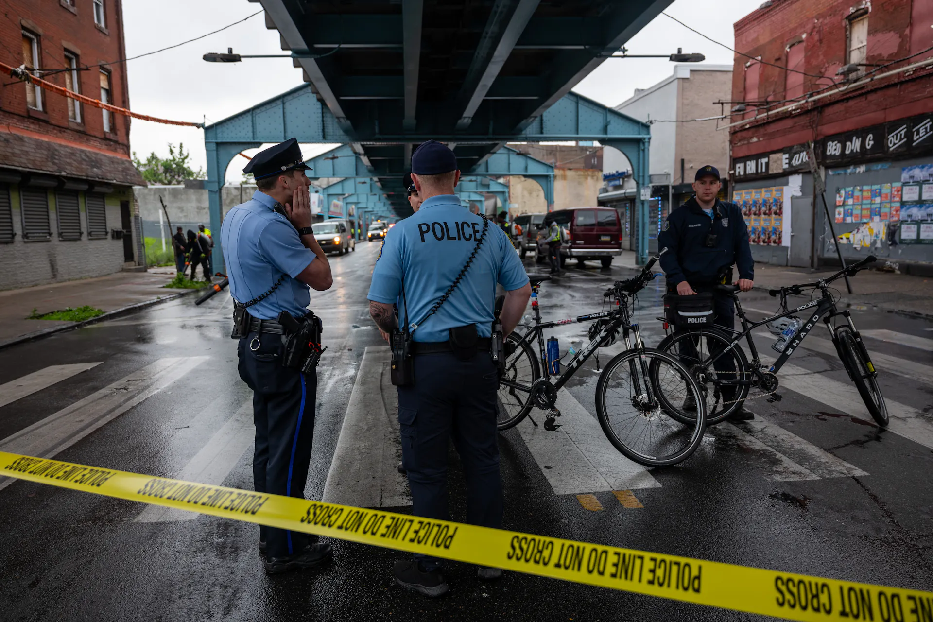 Uniformed police officers gather under underpass behind yellow police tape
