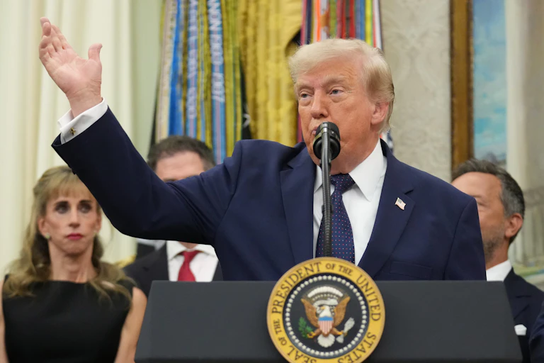 An old white man in a suit speaks from behind a podium with the US President seal on it