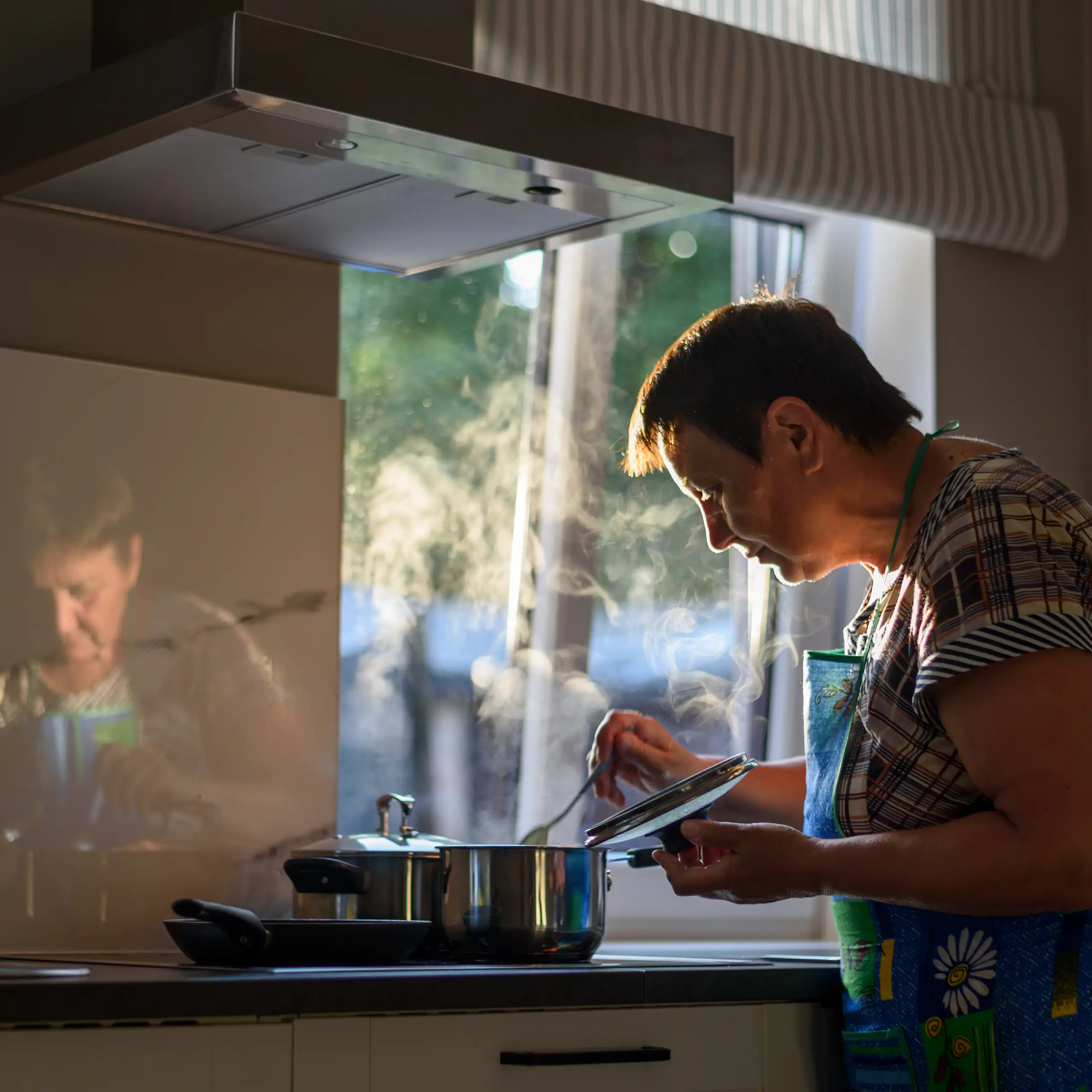 An older woman cooks in her kitchen