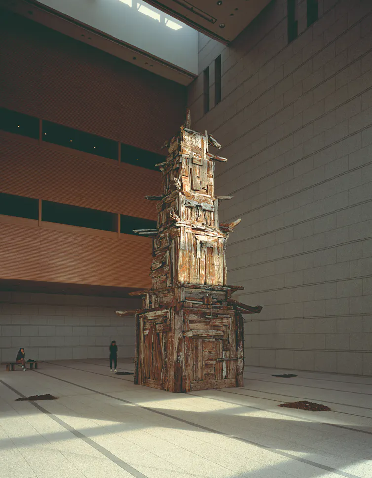 A multi-story gallery space with a pagoda-like structure made of salvaged wood.