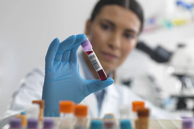 A person holding up a blood sample.