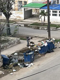 A man looks through trash in the street