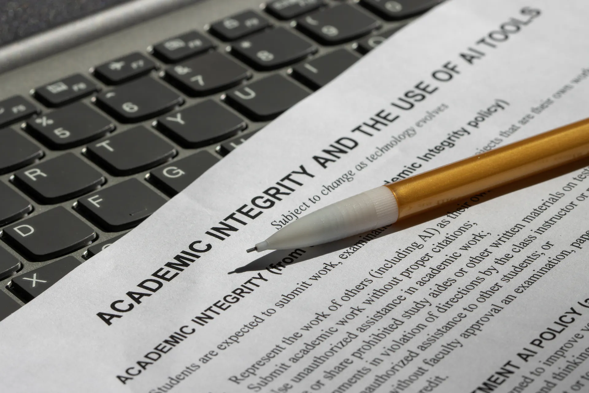 A pencil lies across a paper that says 'Academic integrity and the use of AI tools' with more black text below it.