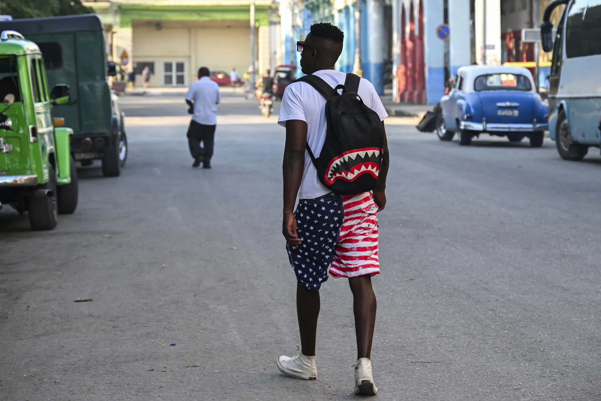 A man wears a backpack and red, white and blue shorts.