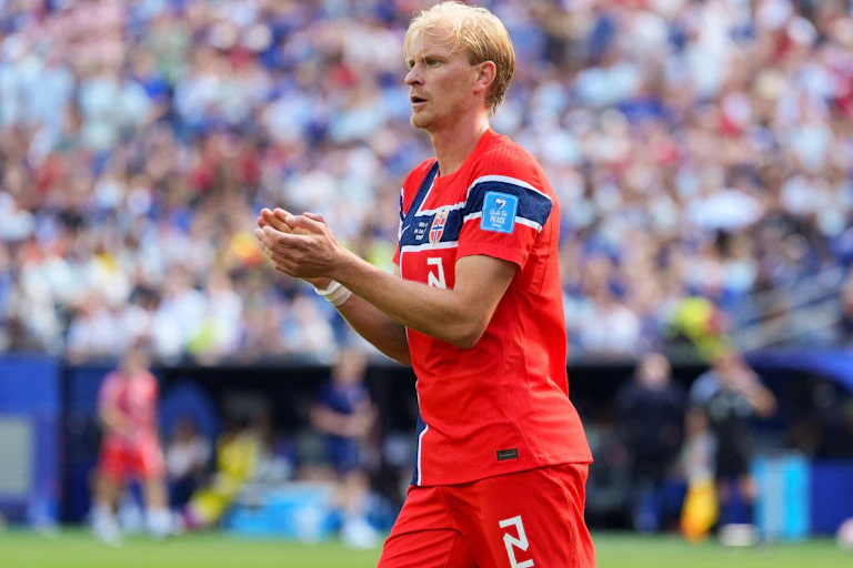 norwegian blonde footballer in kit, stands on pitch clapping hands