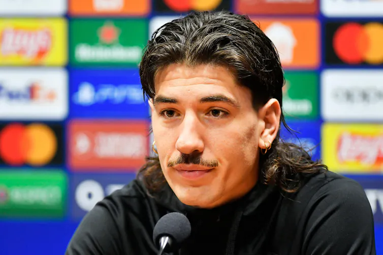 dark haired football player, sitting down with microphone at press conference