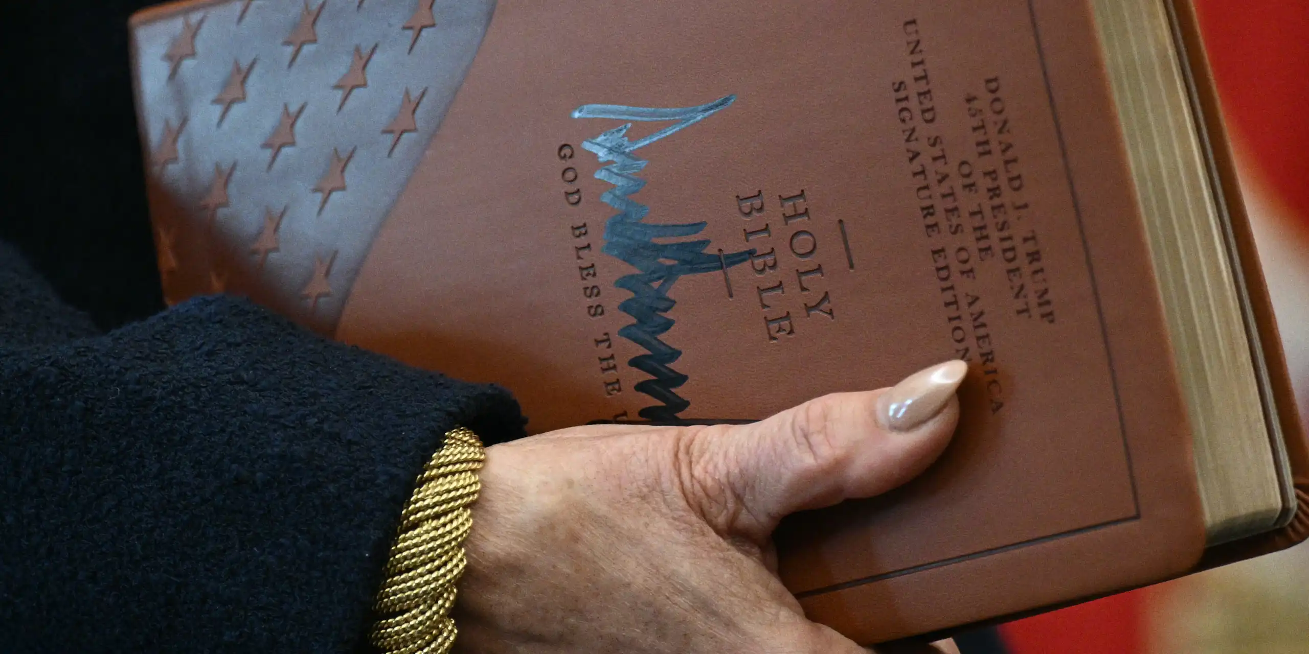 Gros plan sur les mains de la procureure tenant la Bible et la signature de Trump sur la couverture.