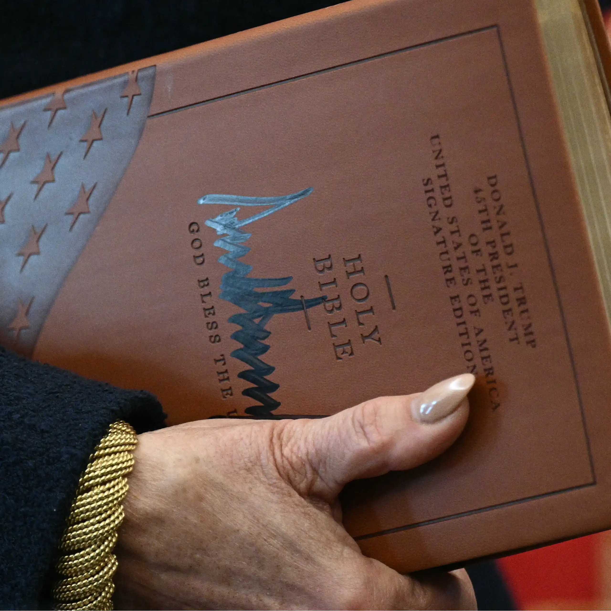 Gros plan sur les mains de la procureure tenant la Bible et la signature de Trump sur la couverture.