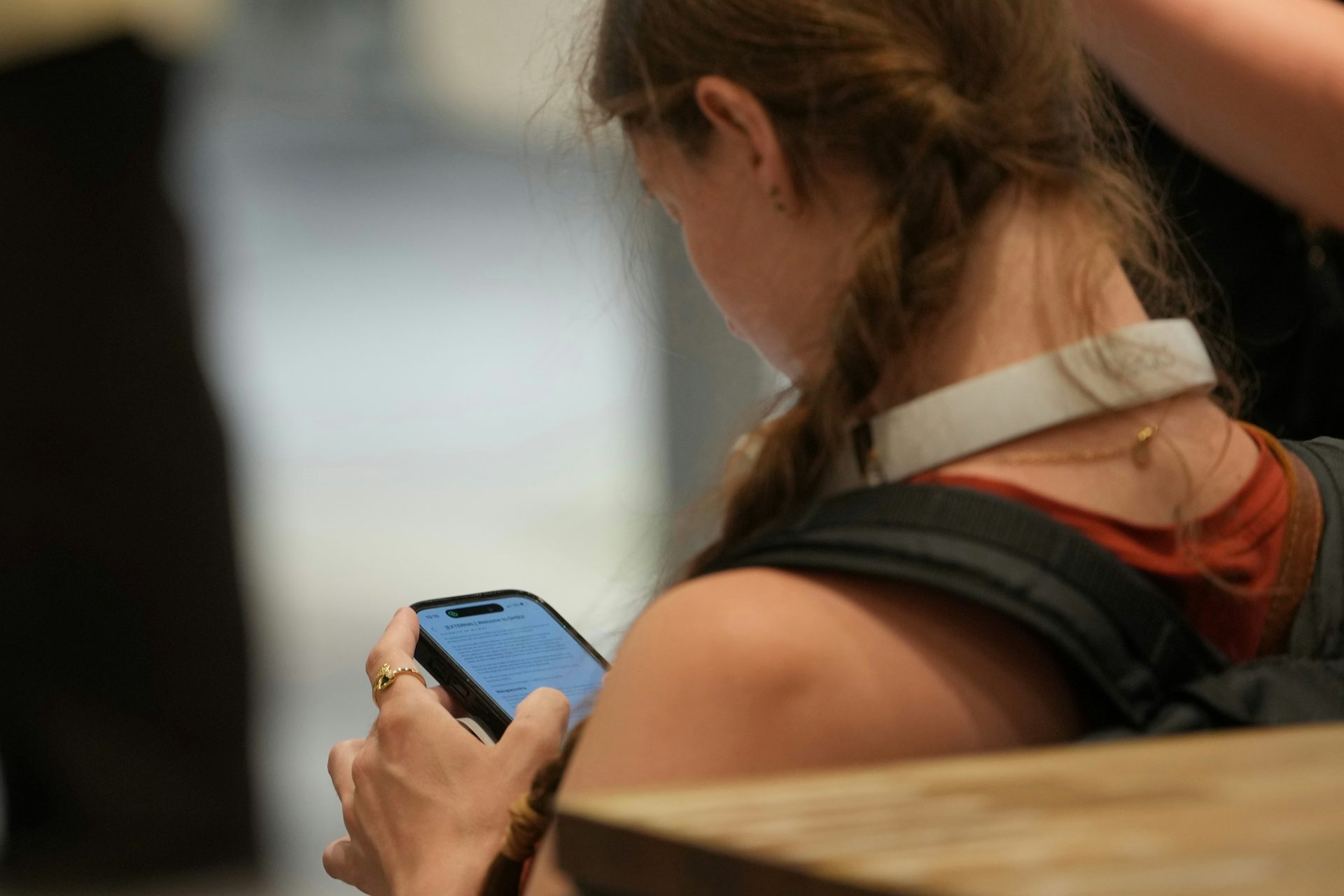 Une jeune fille, vue de dos, regarde son téléphone portable