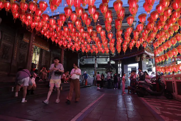Democracia de primera línea: cómo Taiwán y la diáspora taiwanesa luchan contra el aislamiento global 1 La gente camina de noche bajo hileras de faroles rojos.