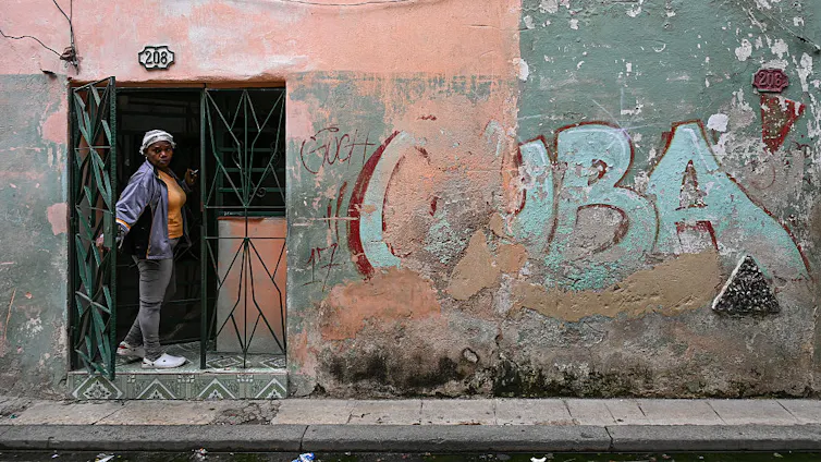 CUBA is written on a wall as a woman peaks out