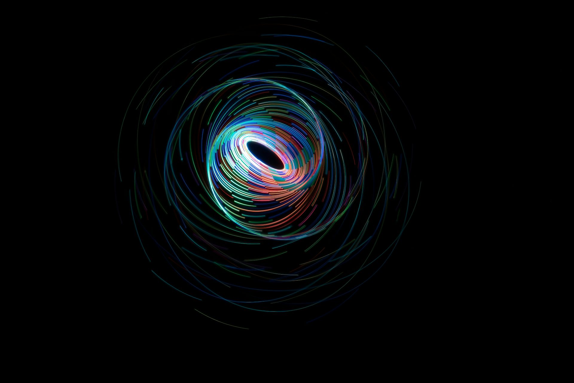 Uma ilustração de linhas em espiral contra um fundo preto, formando uma espécie de buraco negro ou vórtice.