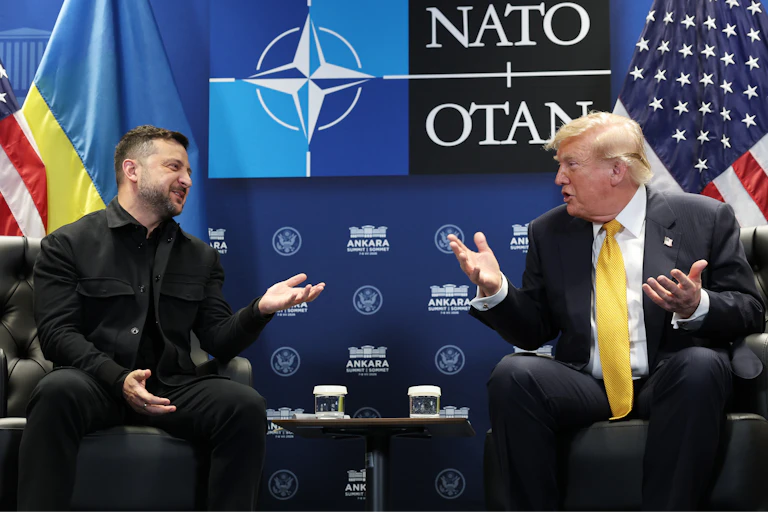Two men in suits sit and talk.