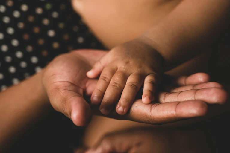 A black mother holds her baby's hand